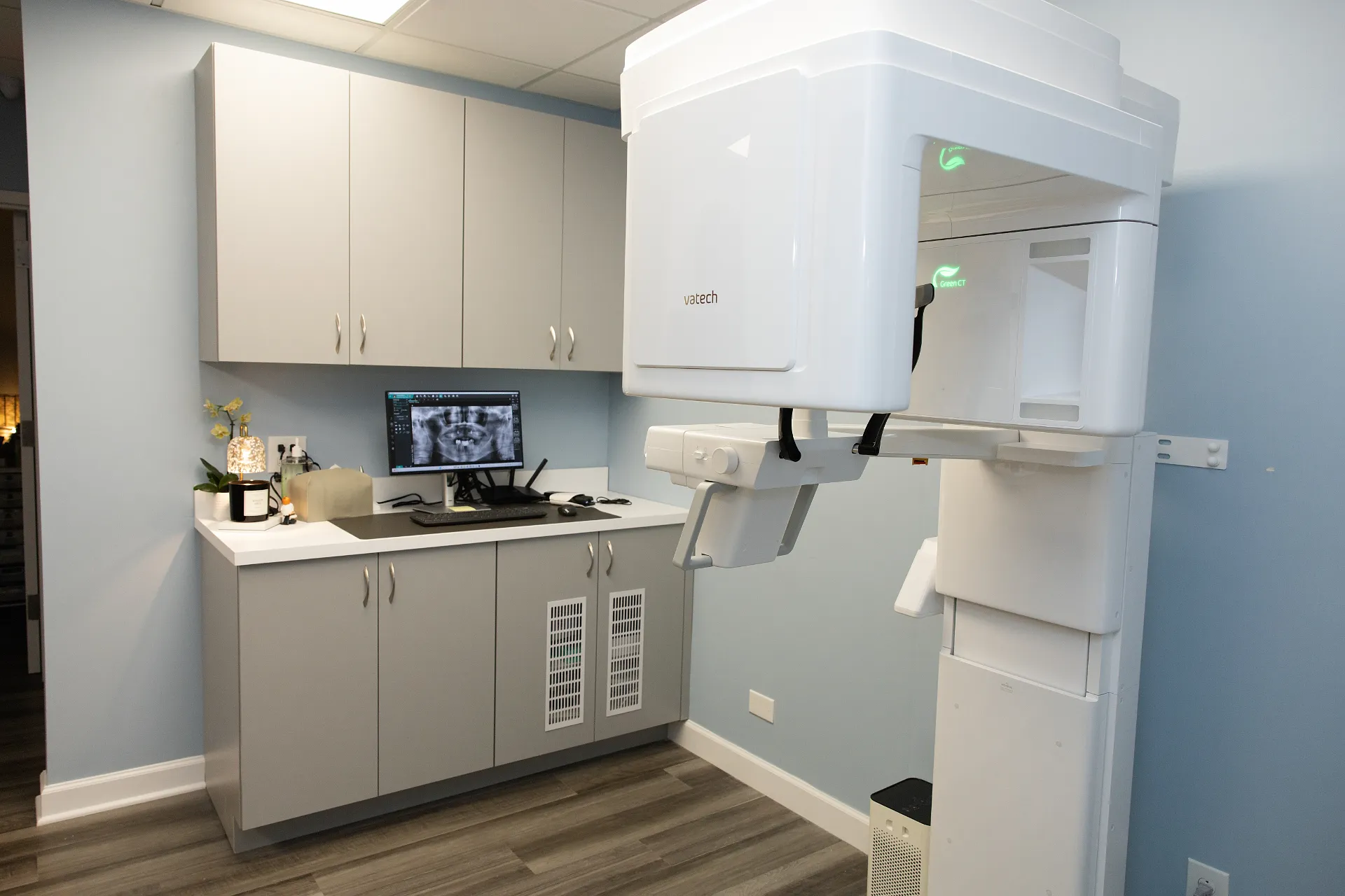 Large Vatech CBCT scanner in a dental imaging room with grey cabinetry and a monitor showing dental X-rays — My Dental Hub in Skokie, IL