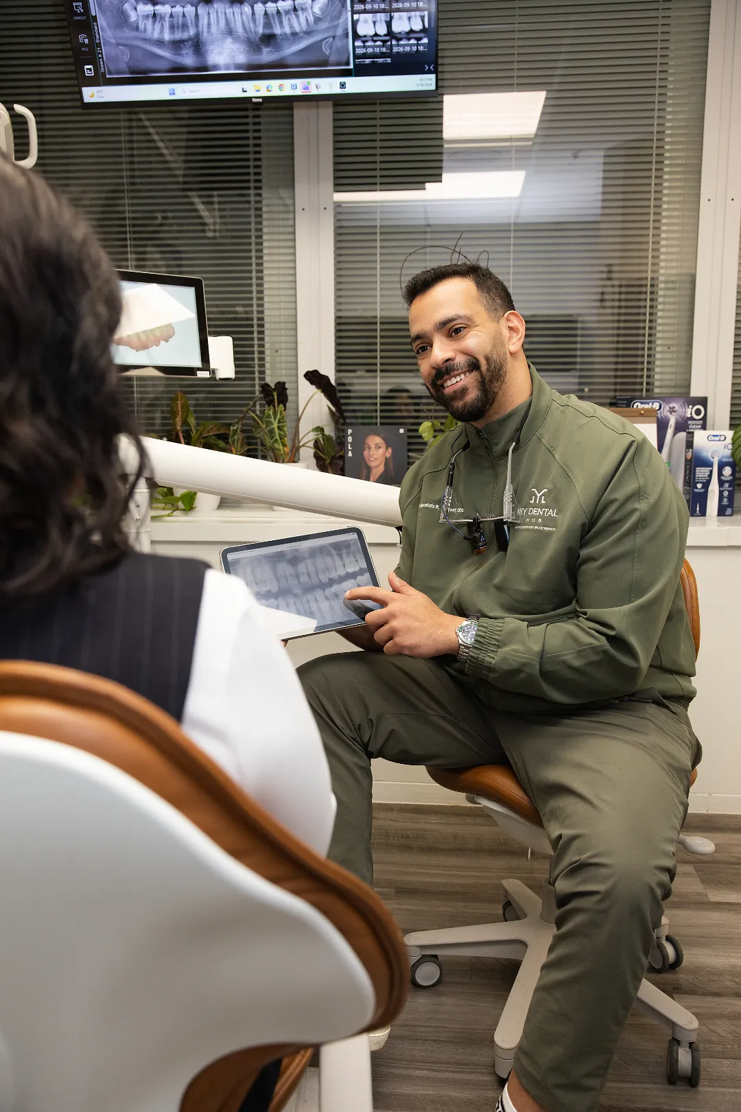 Dentist pointing at a digital x-ray on a tablet while discussing treatment with a patient in an operatory — My Dental Hub in Skokie, IL
