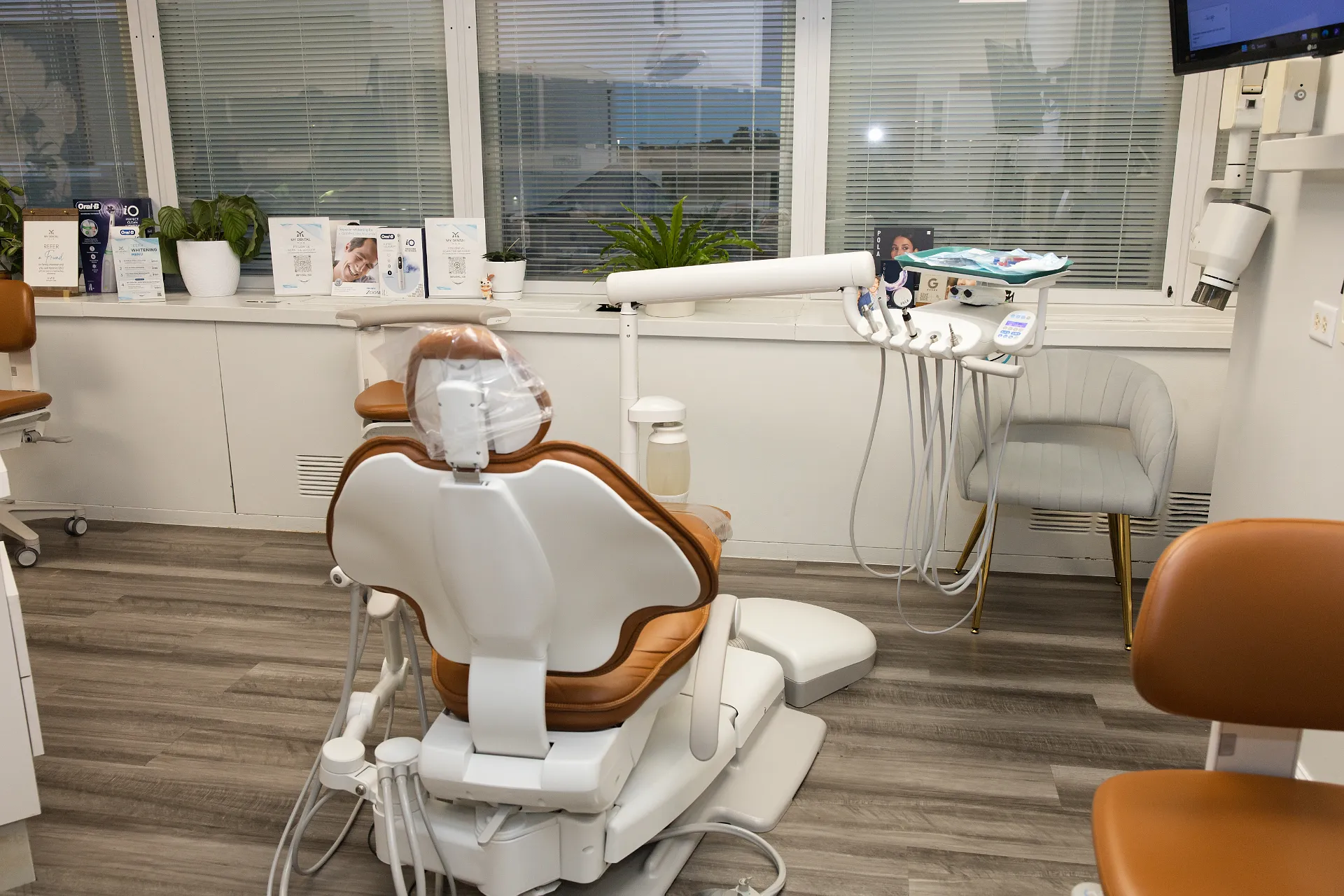 Dental treatment chair in tan and white with attached delivery system and overhead light — My Dental Hub in Skokie, IL
