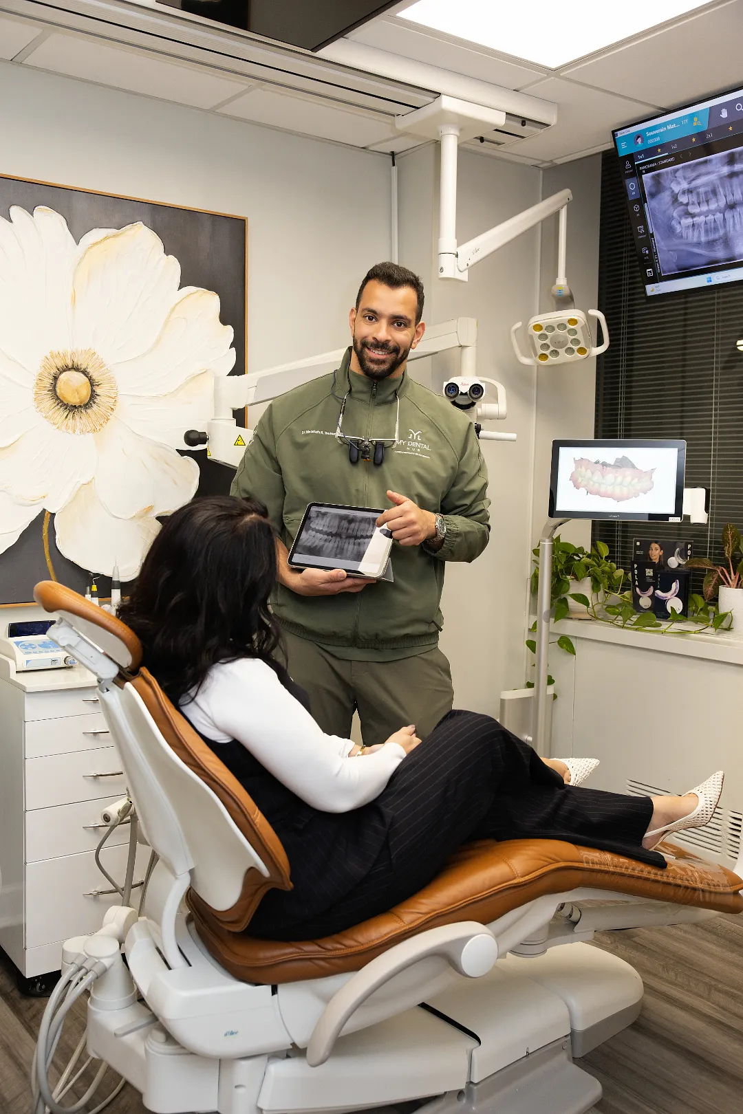 Dentist holding a tablet showing radiographs while consulting with a female patient in a dental chair — My Dental Hub in Skokie, IL