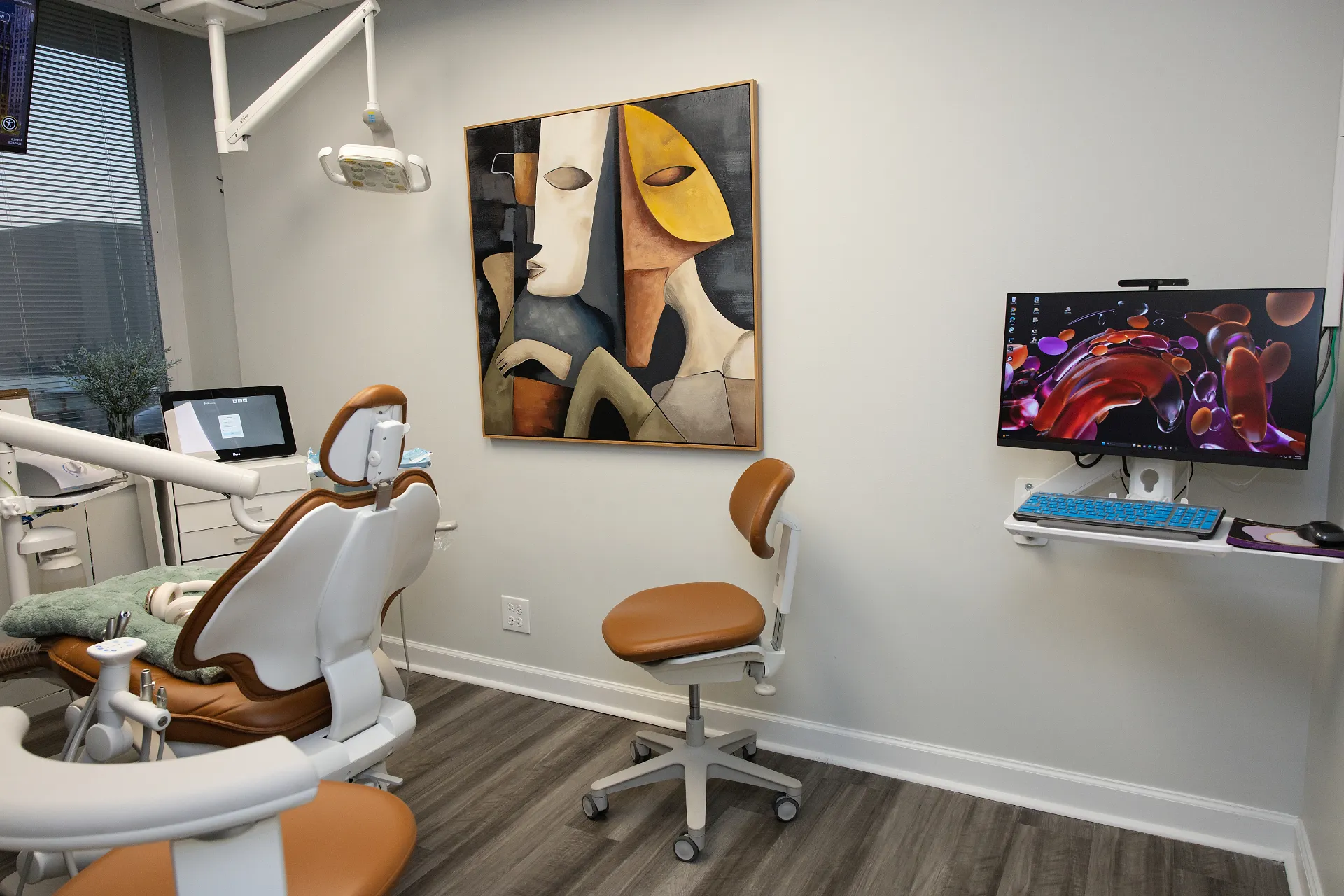 Dental operatory with brown and white dental chair, stool, wall-mounted monitor, and abstract artwork — My Dental Hub in Skokie, IL