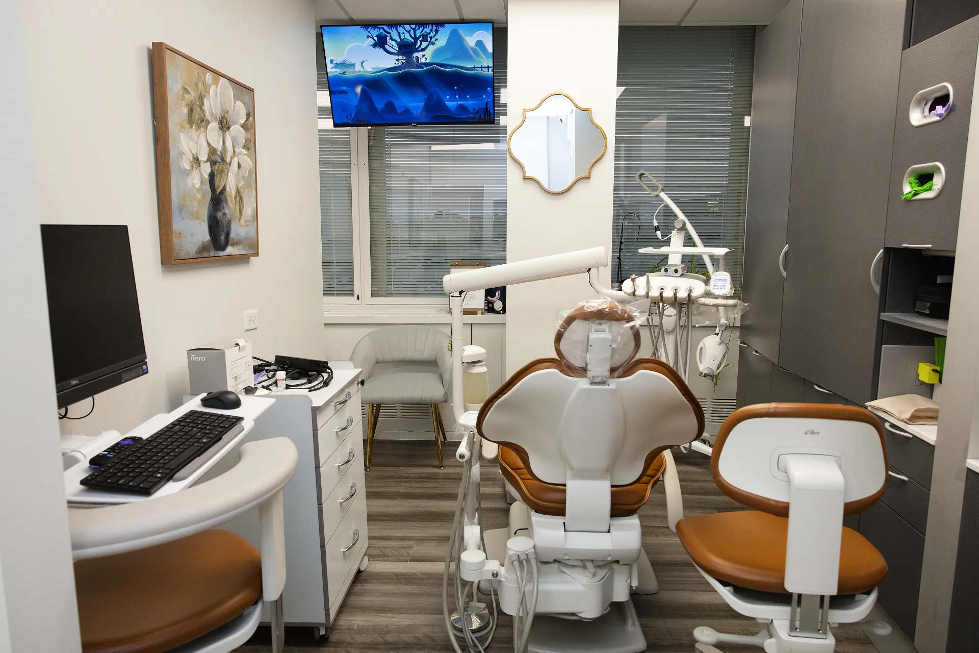 Modern dental treatment room featuring a brown and white chair, computer station, cabinetry, and a wall-mounted TV — My Dental Hub in Skokie, IL