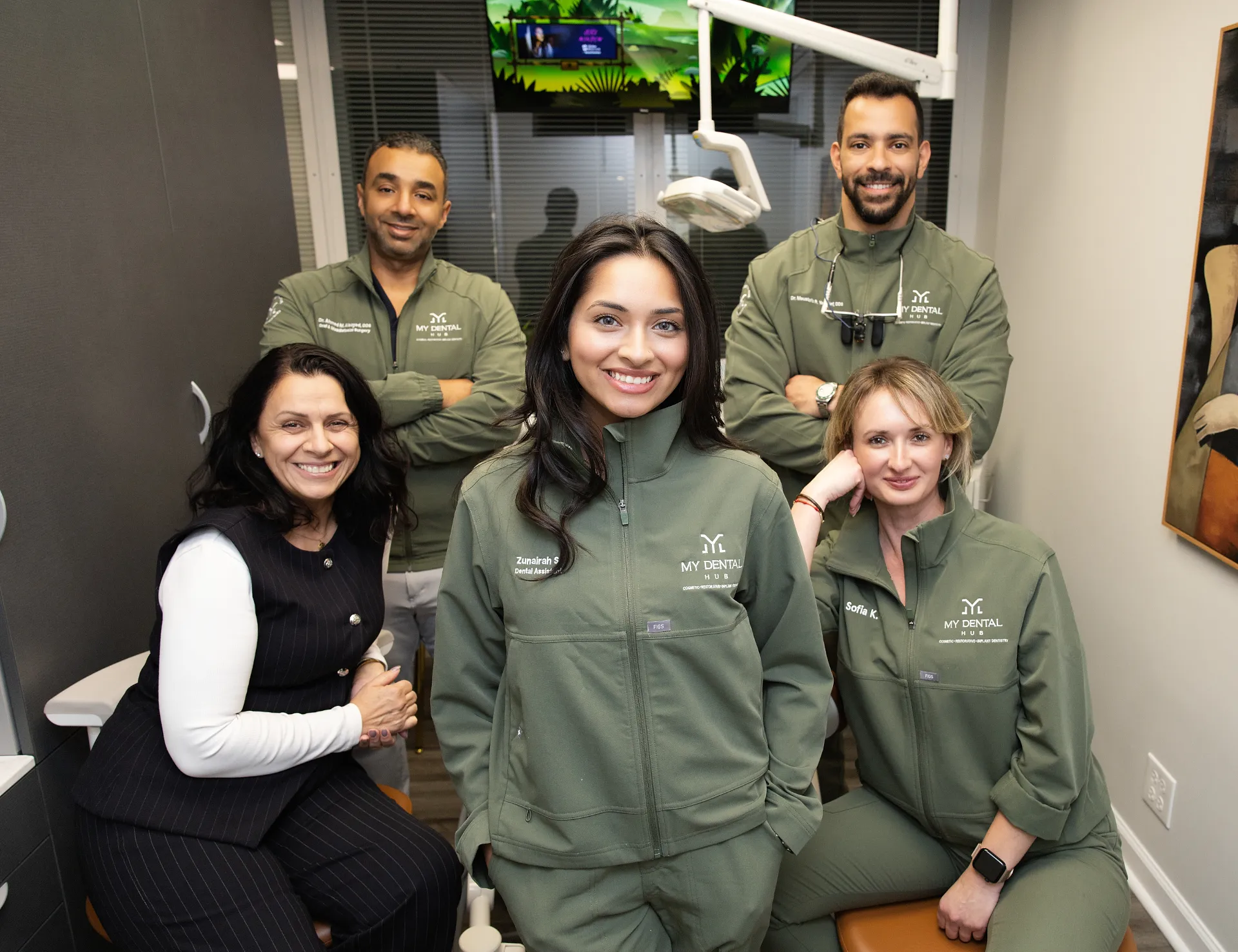 Five dental staff members posing together in an operatory wearing green jackets with My Dental Hub branding — Skokie, IL